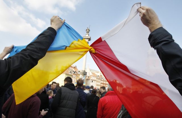 People hold tied Polish, right, and Ukrainian flags during a demonstration supporting the opposition movement in Ukraine, in Warsaw, Poland, Sunday, Feb. 23, 2014. A top Ukrainian opposition figure assumed presidential powers Sunday, plunging Ukraine into new uncertainty after a deadly political standoff - and boosting long-jailed Yulia Tymoshenko's chances at a return to power. The whereabouts and legitimacy of President Viktor Yanukovych are unclear after he left the capital for his support base in eastern Ukraine. (AP Photo/Czarek Sokolowski)