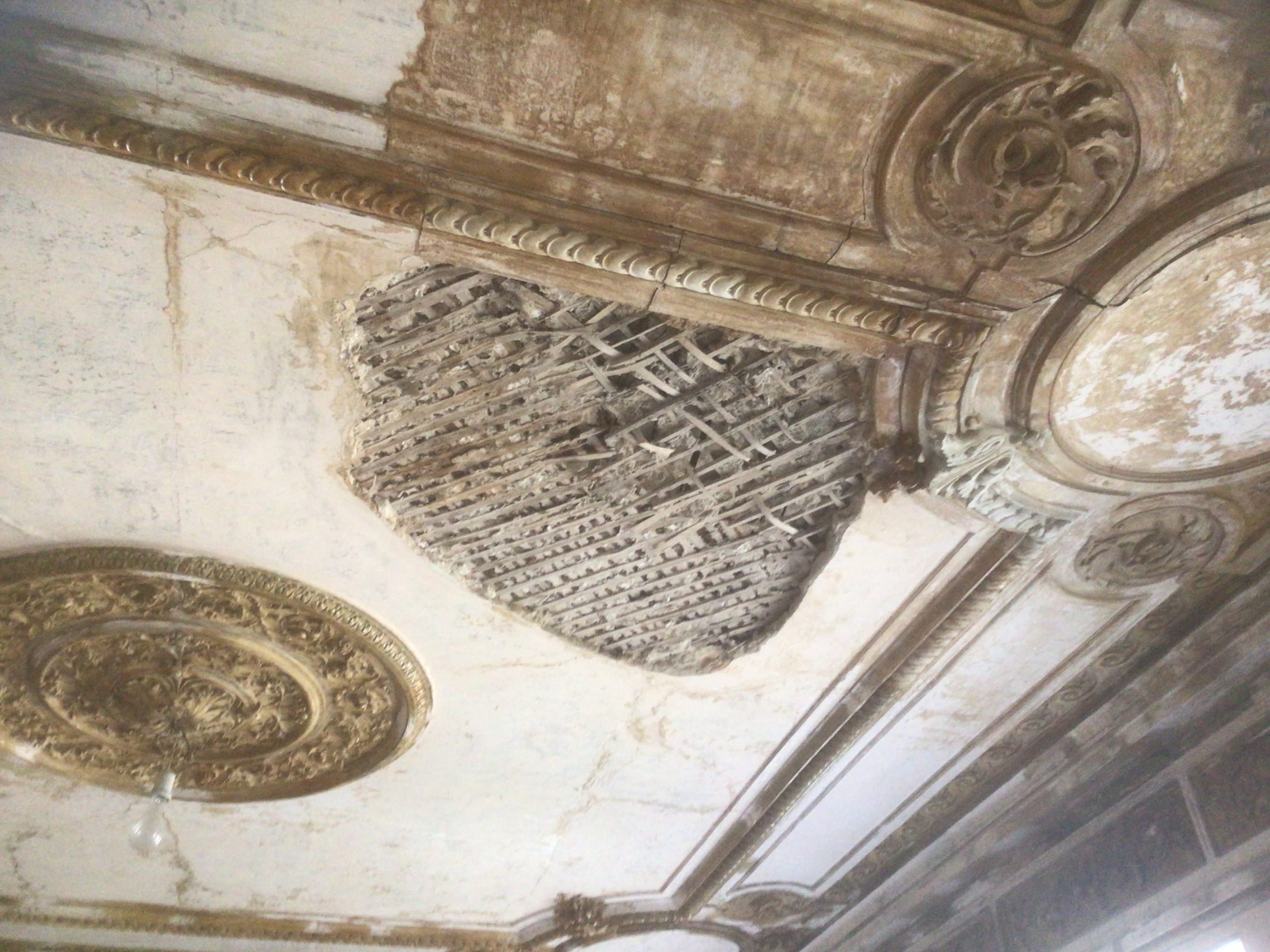A decorated celling of a historical mansion of 19 century after a rocket strike.