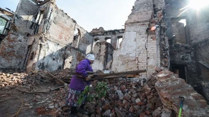 Izyum, Kharkiv region. Woman is collecting wood from the rubbles of a school for cooking on the fire outdoors. As of October 1, 2022 there was no gas, no electricity, no water. Photo was taken on Oct 01, 2022 by Yevhen Tytarenko.